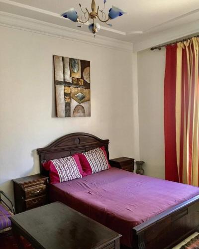 a bedroom with a bed with pink sheets and a ceiling at Vacances à petit prix Lot Shems in Safi
