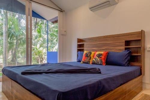 a bedroom with a large bed with a wooden headboard at BunkNBrew in Palolem