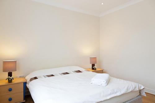 ein weißes Schlafzimmer mit zwei Nachttischen und einem Bett in der Unterkunft Apartments close Spurs stadion station 1 minute away in London