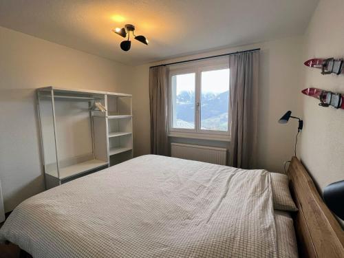 a bedroom with a bed with a ceiling fan and a window at Casa Campanula in Laax