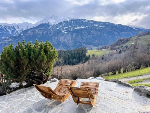 two wooden chairs sitting on top of a mountain at Casa Campanula in Laax