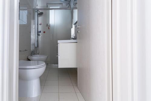 une salle de bains blanche avec toilettes et lavabo dans l'établissement Appartamento climatizzato a 50 m dal mare nel centro di Torre San Giovanni, à Torre San Giovanni