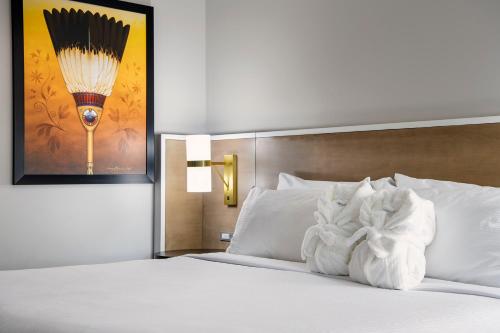a bedroom with a bed with white pillows and a painting at Wyndham Garden Winnipeg Airport in Winnipeg