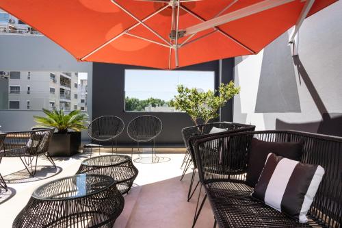 a patio with chairs and tables and an umbrella at Hotel Bys Palermo in Buenos Aires