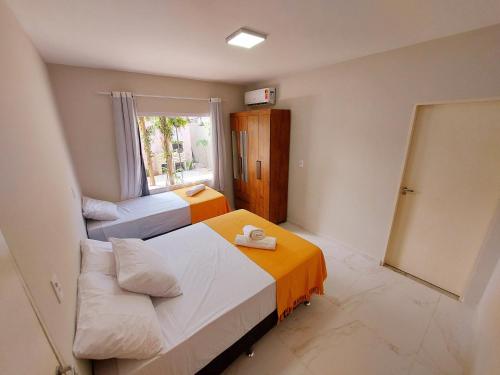 Habitación pequeña con 2 camas y ventana en Mar e Sol Chalés SMG, en São Miguel do Gostoso