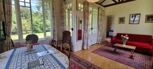 un salon avec un canapé rouge et une table dans l'établissement Chalet au calme en forêt, à Coye-la-Forêt