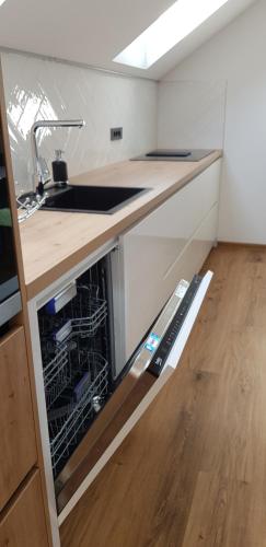 an open dishwasher in a kitchen with a sink at AppPrusnik in Ljubljana