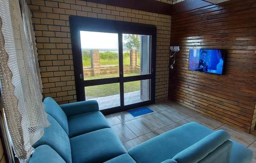 a living room with a blue couch and a tv at Residencial Itapeva in Torres