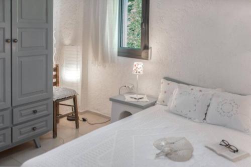 a bedroom with a white bed with a table and a chair at A Cretan house in a garden,overlooking the sea. in Ierapetra