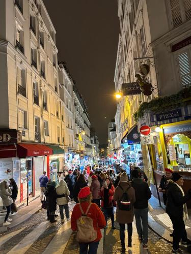 Eine Menschenmenge, die nachts eine Straße entlangläuft. in der Unterkunft studio au cœur Montmartre in Paris