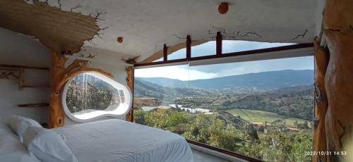 1 dormitorio con cama y ventana grande en Paraiso de Arcilla - Suite & Glamping, en Ráquira