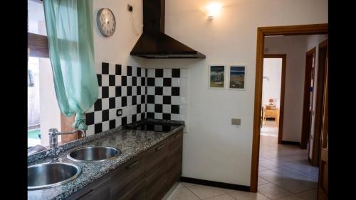 een keuken met twee wastafels en een klok aan de muur bij villa Orchidee Sardegna in Capitana