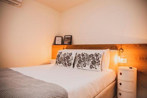 een slaapkamer met een wit bed en een houten hoofdeinde bij Casa de Couros in Guimarães