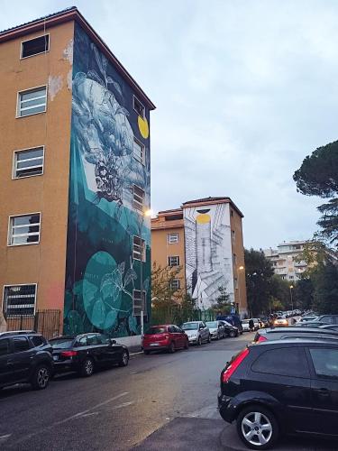 un mural en el lateral de un edificio con coches aparcados en Grazioso Loft vicino a San Giovanni e Metro C en Roma