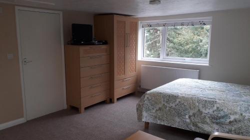 a bedroom with a bed and a dresser and a window at Old Orchard Studio in Froggatt