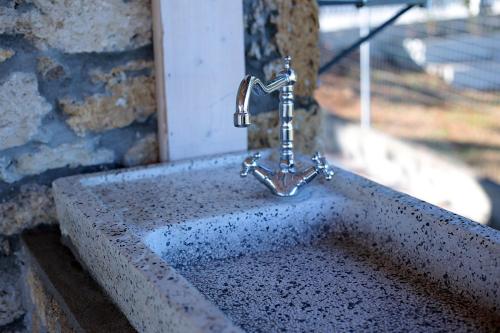 a sink with a faucet on a stone wall at Managraia in Makrýgialos