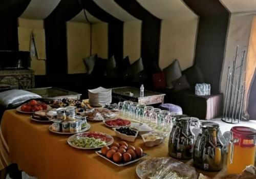 a table with food and drinks on it at Merzouga best camp in Merzouga