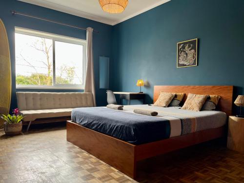 Dormitorio azul con cama y ventana en Azores Bagus Surf House en Ponta Delgada