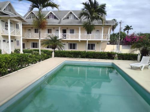 Club Caribbean Apartments في راناوي باي: منزل به مسبح امام مبنى