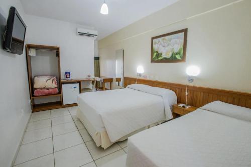 a hotel room with two beds and a television at Foz Presidente Economic Hotel in Foz do Iguaçu