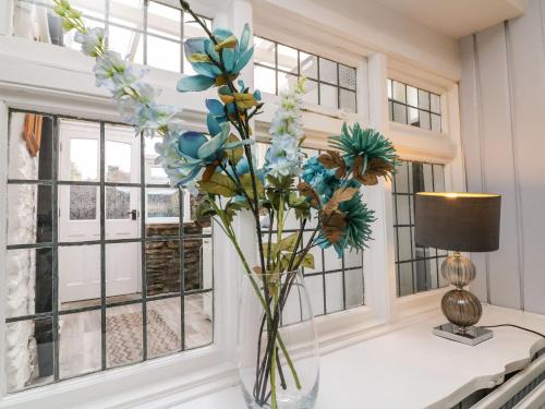 un jarrón de flores sobre una mesa en una habitación con ventanas en Tythe Barn House, en Ilfracombe