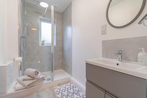 a bathroom with a shower and a sink and a mirror at Wren Cottage in Stratford-upon-Avon