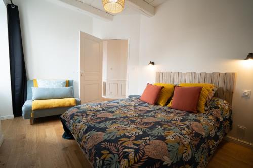 濱海拉普蘭的住宿－Appartement cosy en cœur de bourg，一间卧室配有一张带色彩缤纷枕头的床和一把椅子
