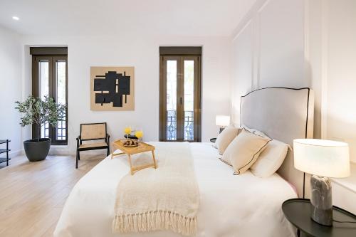 a white bedroom with a large bed and a table at BHost - Ferraz 74 in Madrid