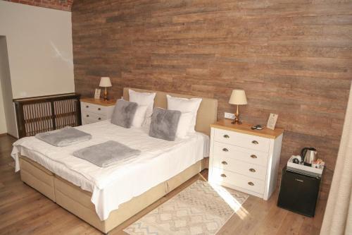 a bedroom with a bed and two dressers and a wooden wall at ELEGANT ROOMS - ULTRACENTRAL - jacuzzi cu hidromasaj in Oradea