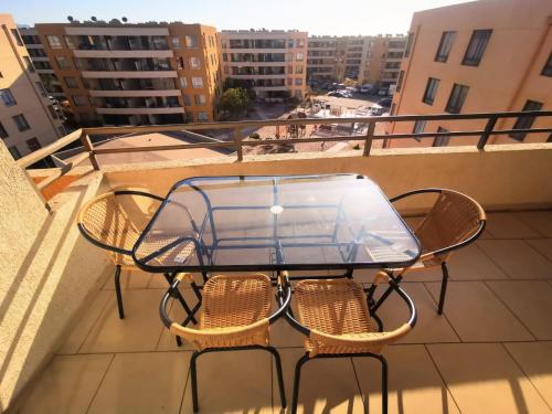 a glass table and chairs on a balcony at Departamento Portal del Norte 1 in Arica
