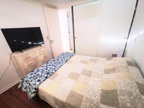 a bedroom with a bed and a flat screen tv at Departamento Portal del Norte 1 in Arica