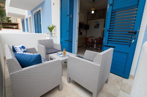 a patio with chairs and a table and a blue door at MARE e Terra Holiday fronte mare in San Vito lo Capo