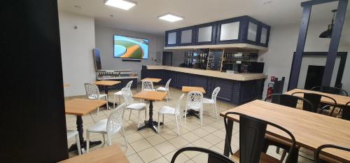 Un restaurante con mesas y sillas y una cocina. en Coliwork Le Saint Romain, en Dangé