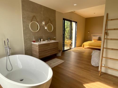 a bathroom with a tub and a bedroom with a bed at Le Domaine du Cade-Gîtes d'exception 4étoiles "La Villa du Cade" in Cazevieille