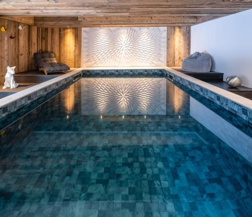 a swimming pool in a house with a wooden ceiling at Chalet Amis - Meribel - Pool moovie and play room in Méribel