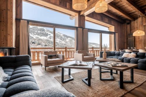 a living room with couches and a large window at Chalet Amis - Meribel - Pool moovie and play room in Méribel