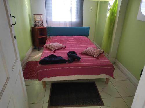 ein Bett mit einer rosa Decke und Kissen darauf in der Unterkunft Chez Axel in Le Marin
