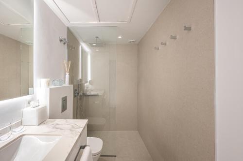 uma casa de banho branca com um lavatório e um WC em Puente Romano Hotel Apartment Marbella em Marbella