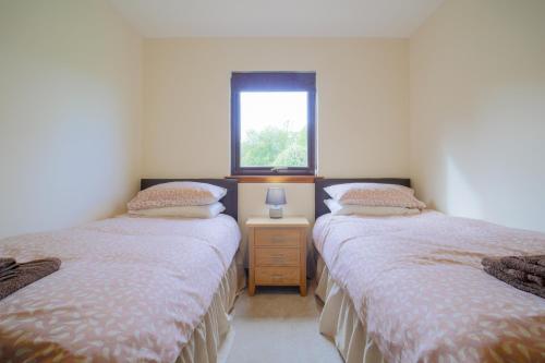 two twin beds in a room with a window at Glenview Chalet Park in Inverness