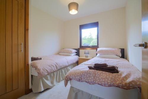 two beds in a small room with a window at Glenview Chalet Park in Inverness