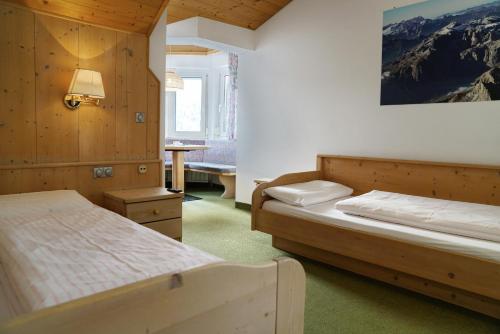 a bedroom with two beds and a table in it at Piz Alpin B&B in Colfosco