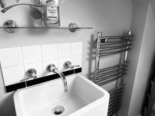 W łazience znajduje się biała umywalka i lustro. w obiekcie Charminster Homestay w Bournemouth