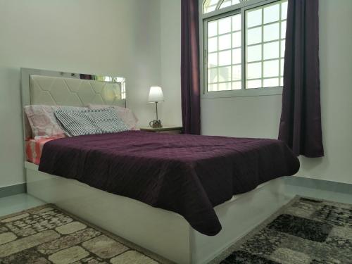 Muscat Homestay & Hospitality في مسقط: غرفة نوم مع سرير أرجواني مع نافذة