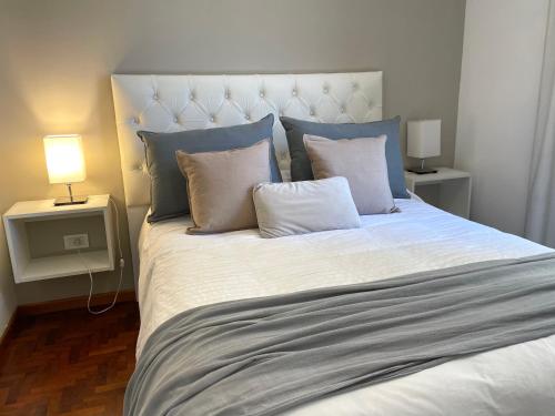 a bedroom with a large bed with blue and white pillows at Balcarce Deluxe in Córdoba