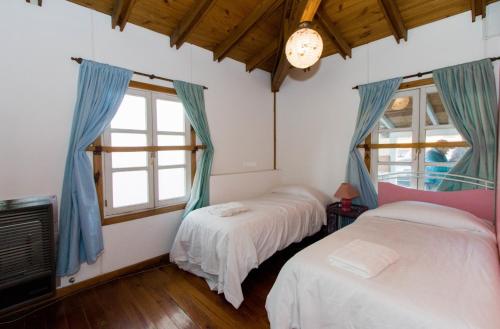 2 Betten in einem Zimmer mit 2 Fenstern in der Unterkunft Gray Fox Apartments Casa La Rafaela in Ushuaia