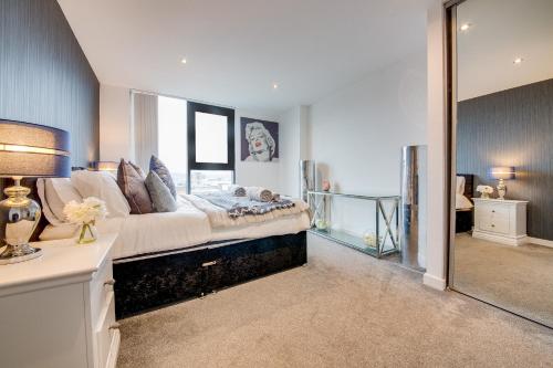 een slaapkamer met een groot bed en een spiegel bij Spacious 3-Bed Penthouse with City Sky Line Views in Sheffield