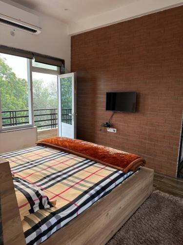 um quarto com uma cama grande e uma televisão numa parede de tijolos em Kaashi Flora - Luxury 3BHK em Varanasi