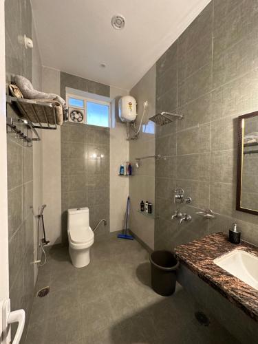 a bathroom with a white toilet and a sink at Kaashi Flora - Luxury 3BHK in Varanasi