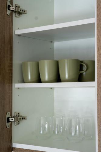 a cupboard with green bowls and glasses in it at LAM Green - AC -BALCONY in Bratislava