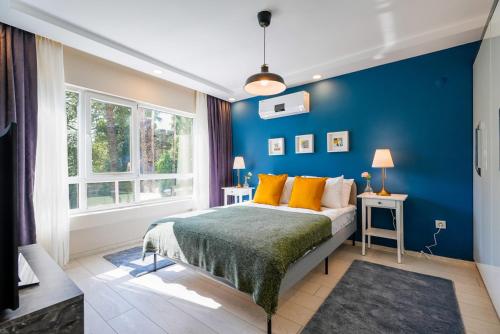 Schlafzimmer mit blauen Wänden und einem Bett mit orangefarbenen Kissen in der Unterkunft Modern Flat near Hadrian's Gate in Antalya